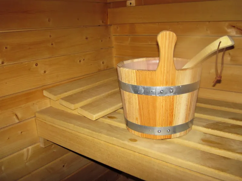 A wooden bucket and ladle resting on a cedar sauna bench