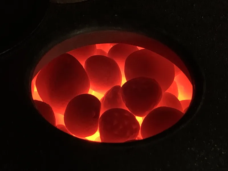Sauna stones glowing orange inside a heat-storage stove